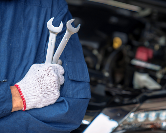 van life mechanic in blue overall and white glove holding tools