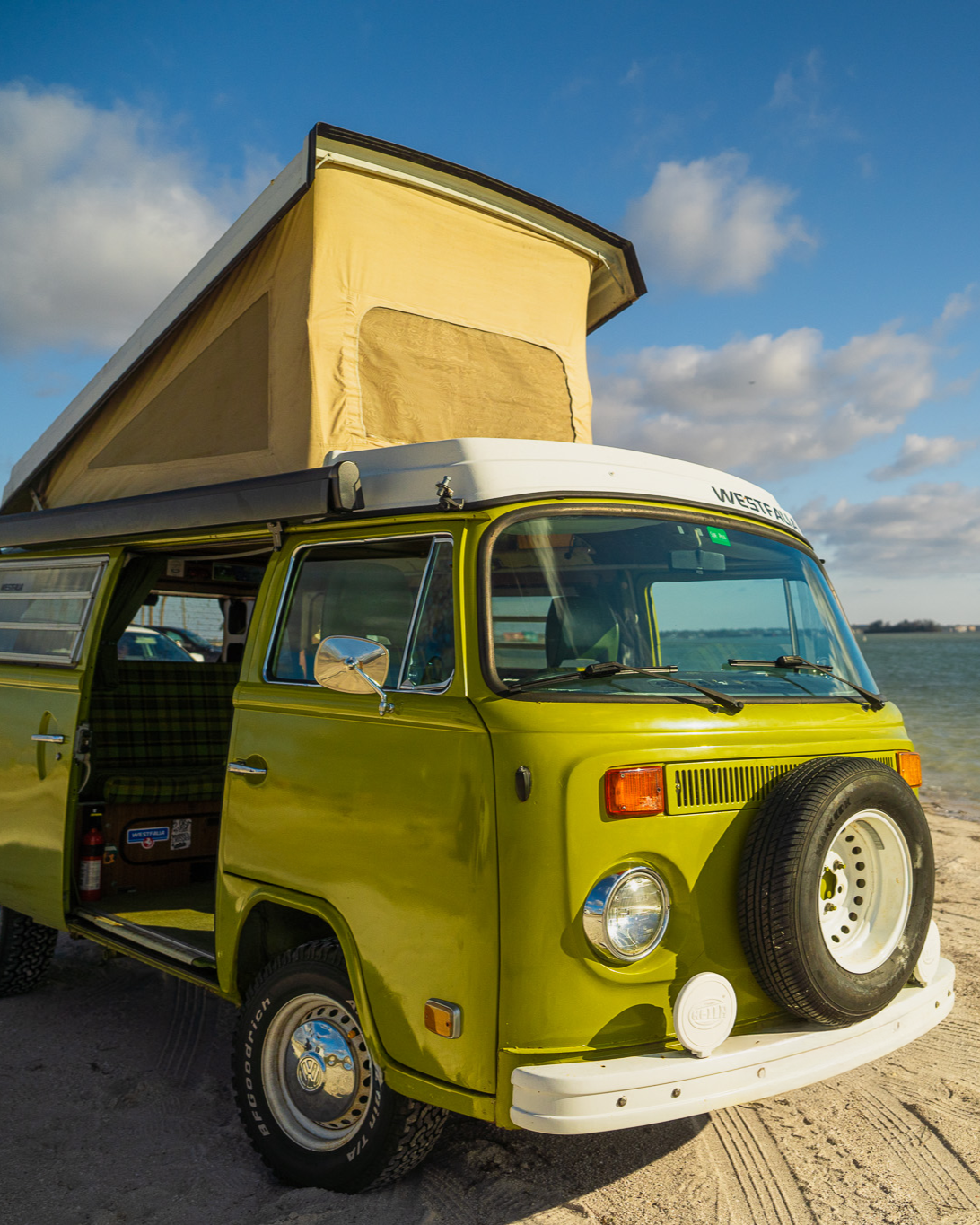 vanlife kiwi volkwagen van with opened door parked at the beach on a sunny day