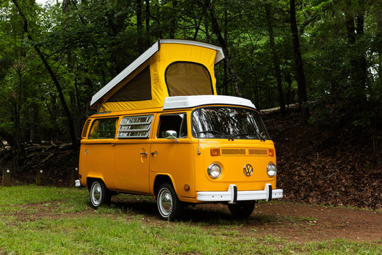vanlife mango van parked on grass in the forest