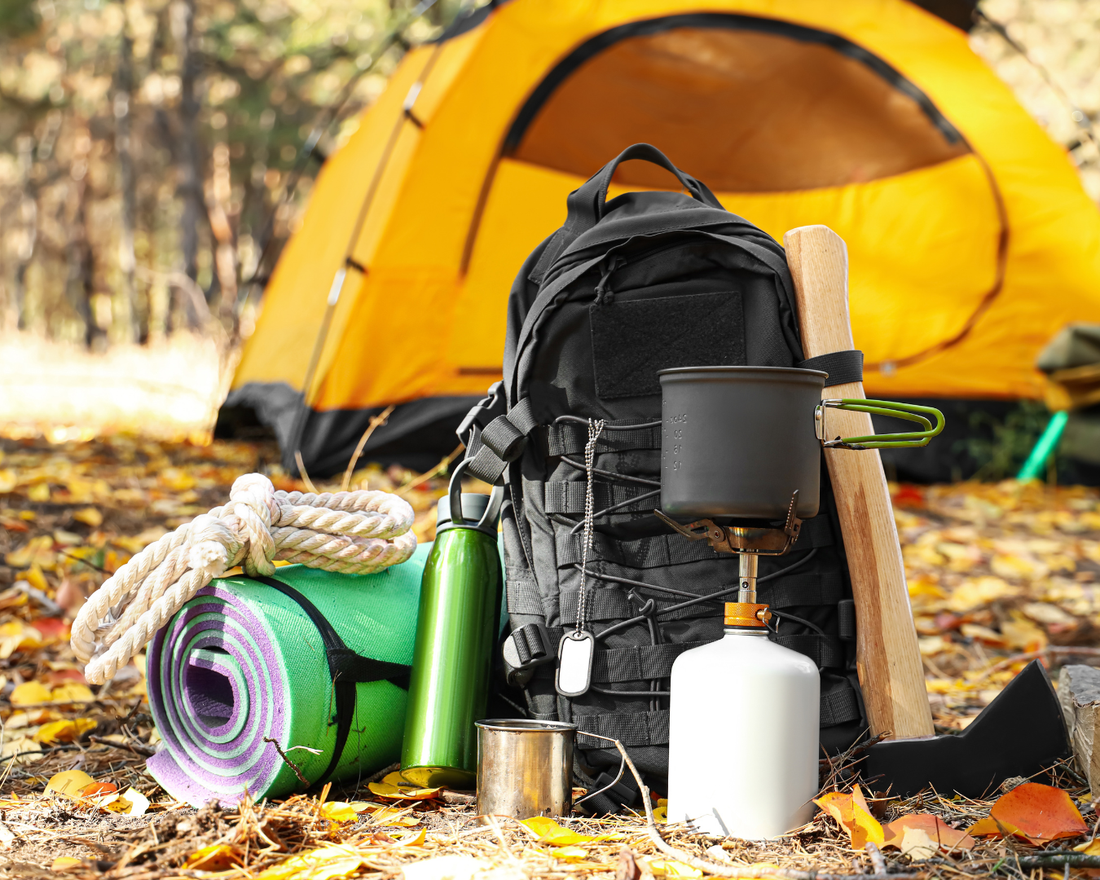 Camping gear resting in wooded area with a yellow camping tent in the background