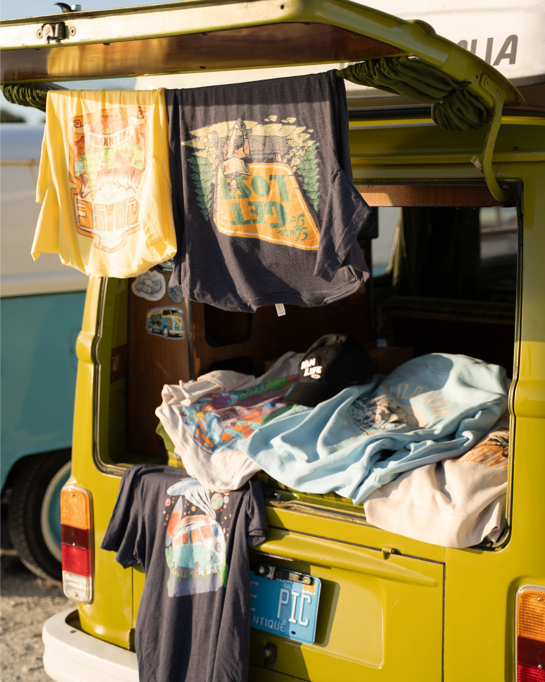 Opened back of the vanlife kiwi Volkswagen van with official vanlife merch hanging from the door and resting inside the van.