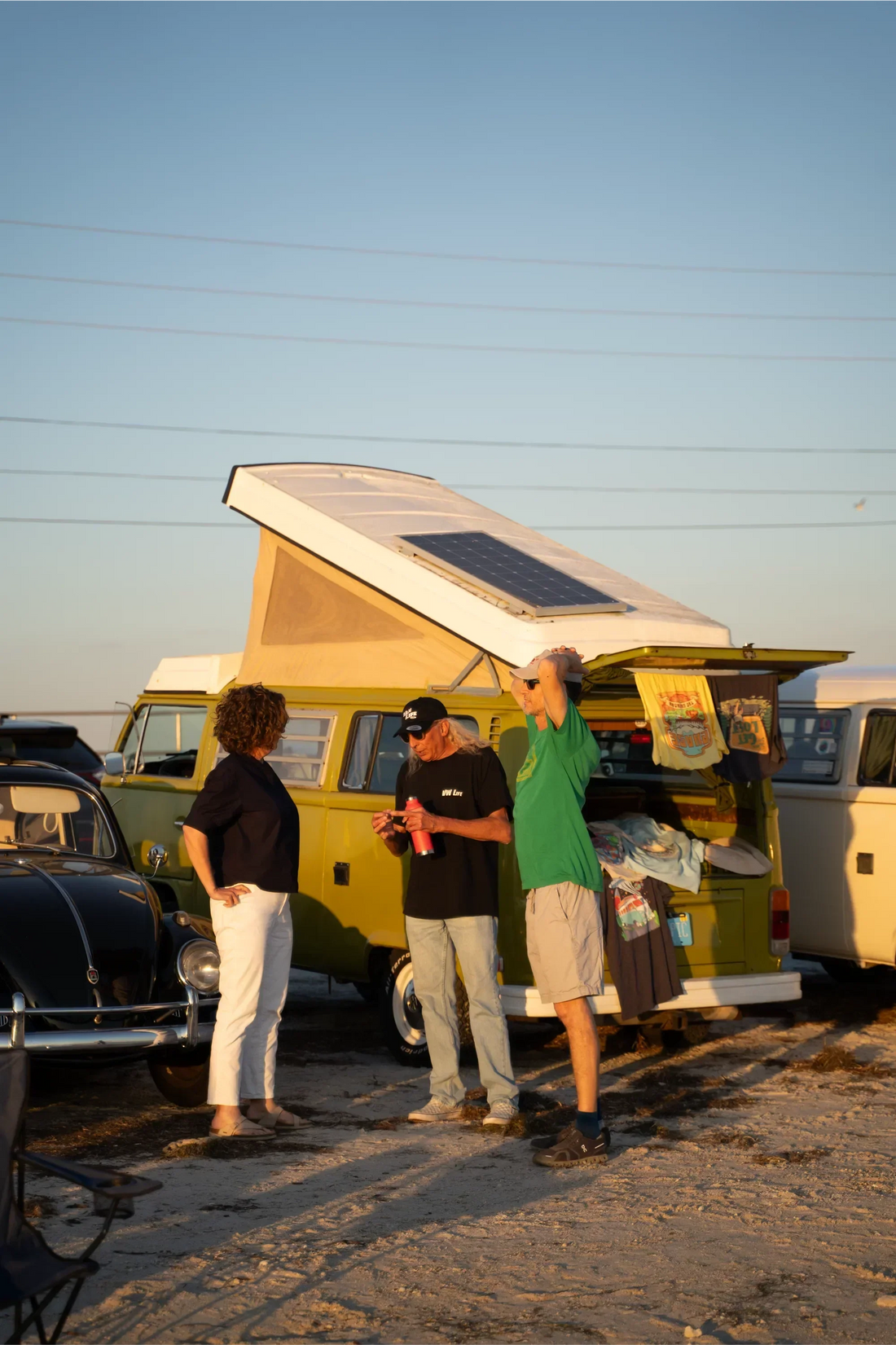 van life folks standing outside of camper van at beach parking lot in the evening time