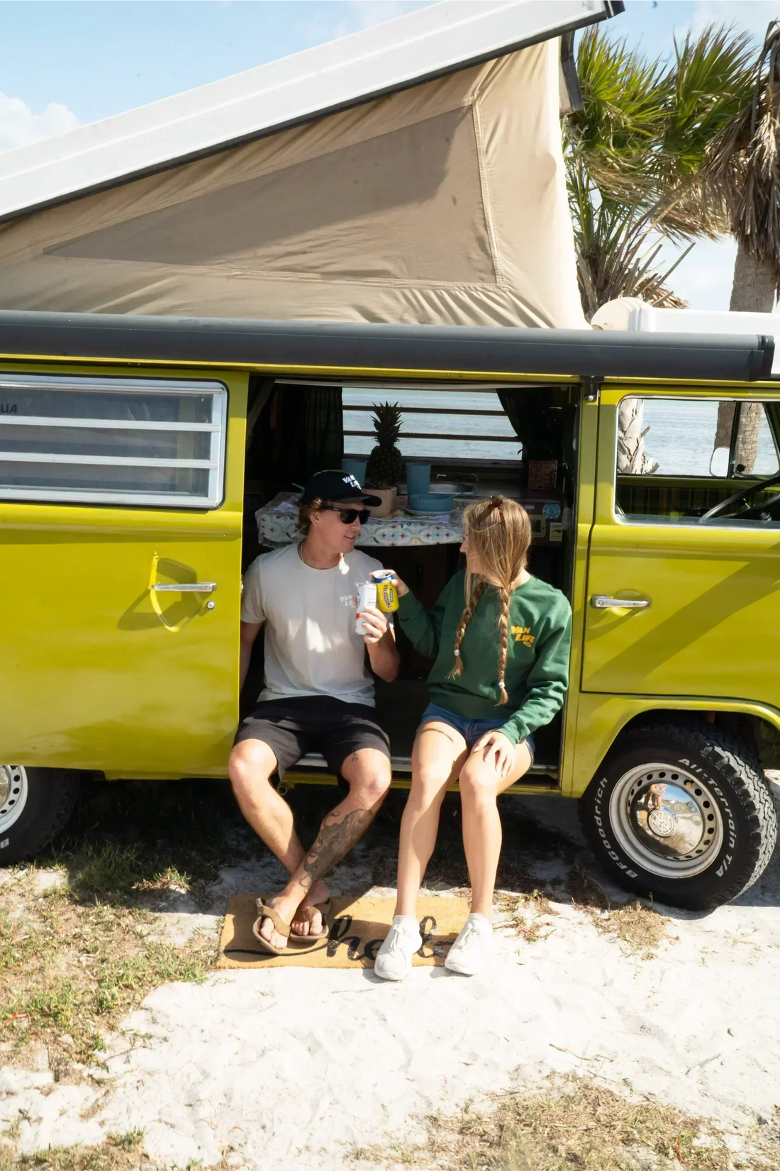 friends sitting in vanlife kiwi van with door opened at the beach