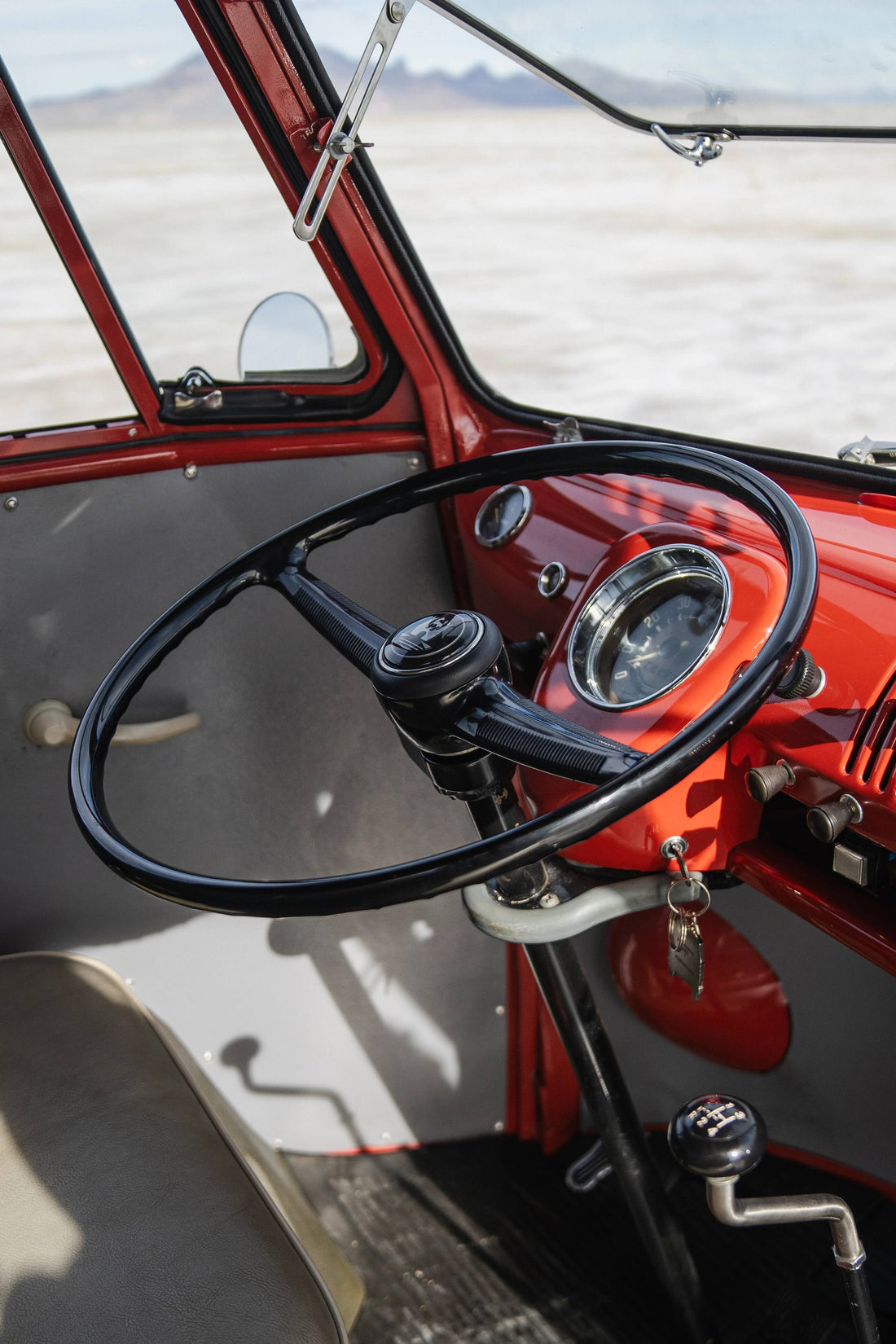 Close-up of a vintage Volkswagen steering wheel and dashboard with a desert landscape in the background.