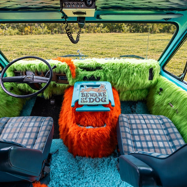The cab seen from the back: green shag dash, orange shag console, plaid seats and teal carpet