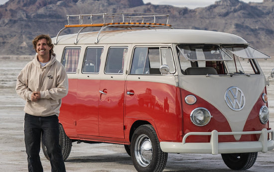 guy standing next to Vanlife 1963 VW Kombi Camper van parked on open plains with mountains in the background