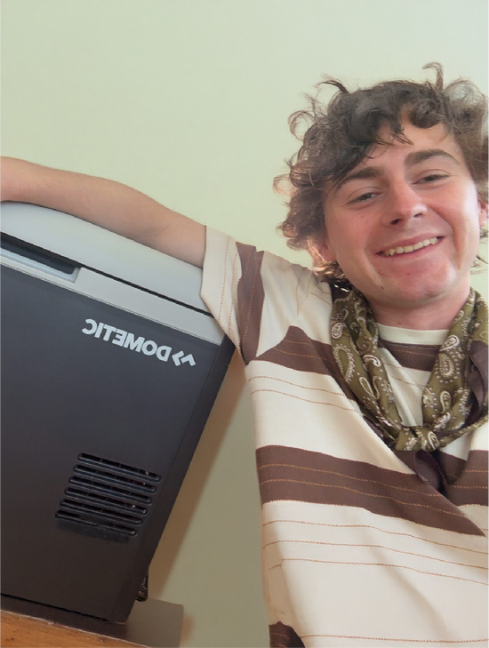 VanLife winner leaning against a Dometic Cooler with a bandana around his neck and a smile on his face.