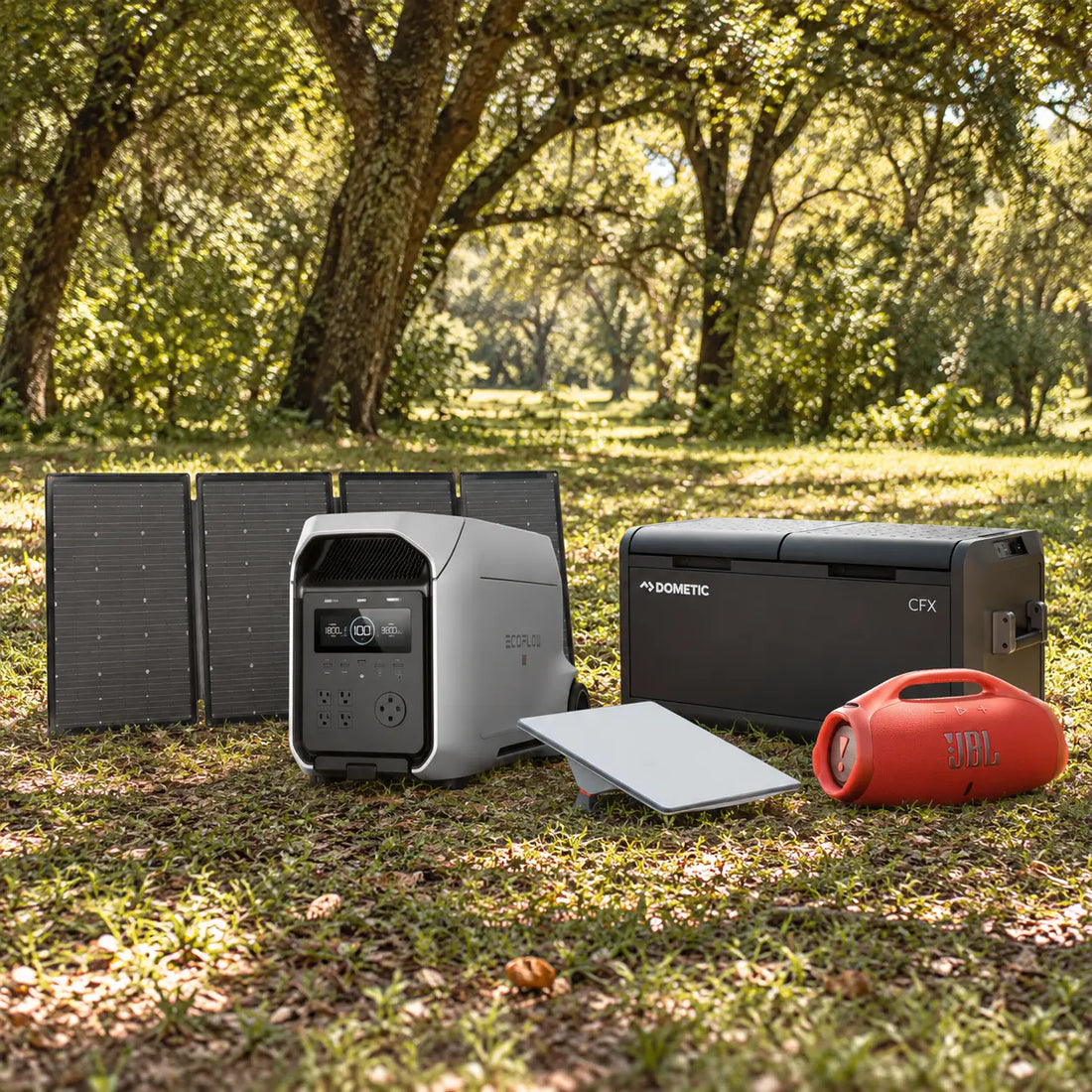 The travel bundle on grass: solar panel, power station, Starlink Mini, cooler and orange speaker