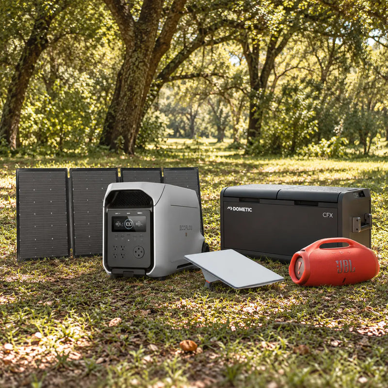 The travel bundle on grass: solar panel, power station, Starlink Mini, cooler and orange speaker
