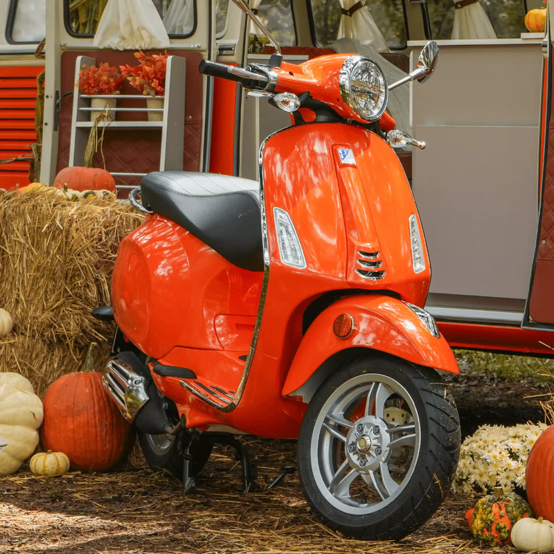 The orange prize Vespa parked beside the orange and white VW Bus