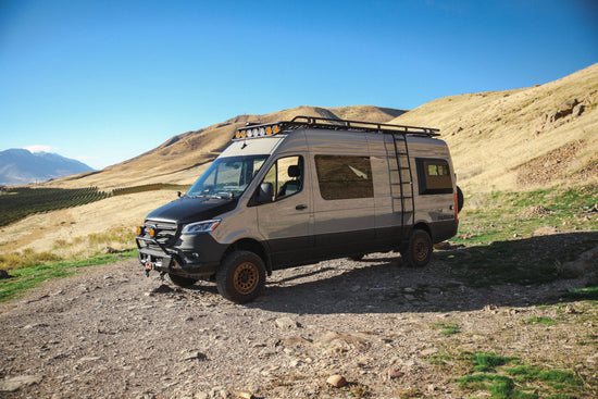 Van life Mercedes Benz Sprinter van parked on dirt road on a mountain side.